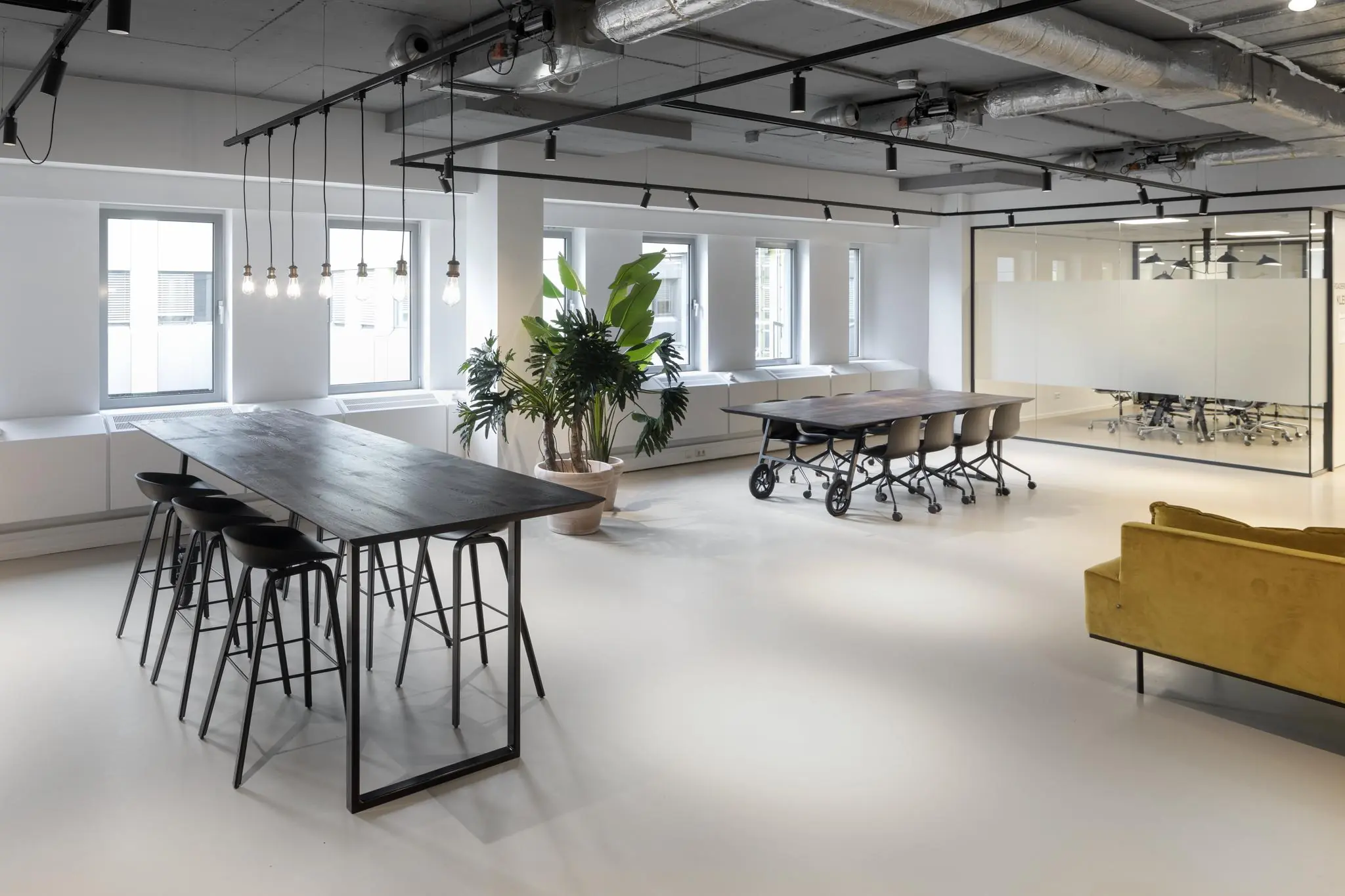 Modern ingerichte kantoorruimte aan de Van Boshuizenstraat met vergadertafels, planten en een glazen vergaderruimte.